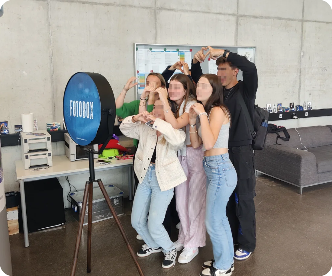 Hochschule – Tag der Unternehmen: Fotobox-Spaß für Besucher Eine Gruppe junger Erwachsener lacht und posiert für ein Foto vor einer blauen Fotobox mit dem Schriftzug „FOTOBOX“.