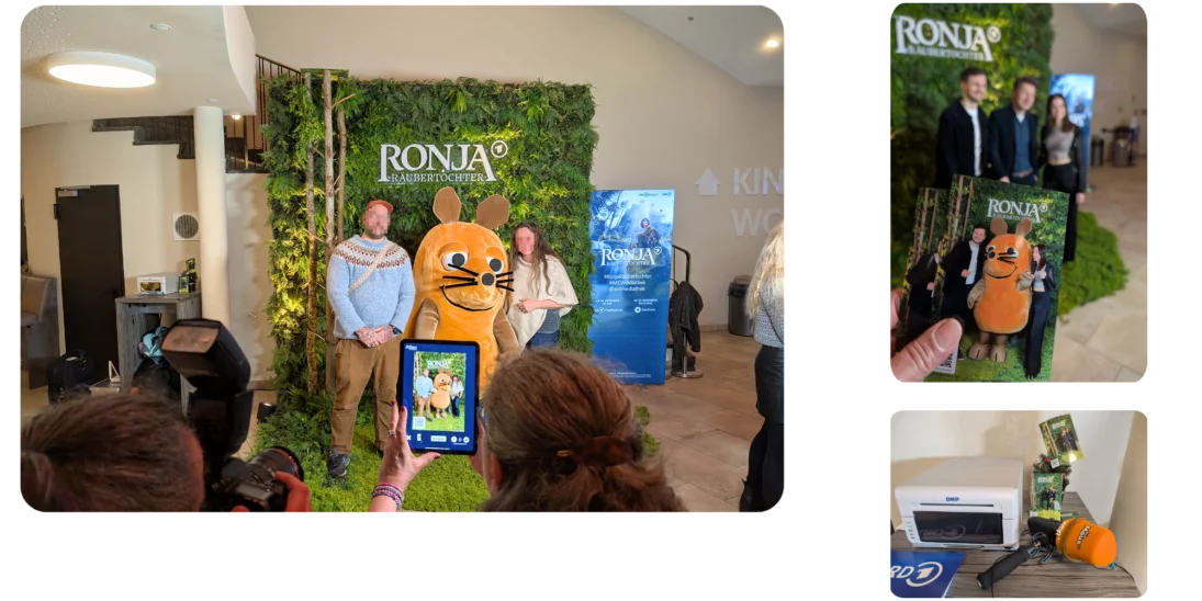 Besucher posieren auf der Kino-Preview von Ronja Räubertochter mit einem Walk Act in einem Biberkostüm. Ein Foto wird live auf dem Handy angezeigt und daneben steht ein Drucker zum Sofortausdruck.